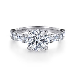 A continuous wall of sparkle greets the recipient of this luxurious 1.22ct diamond engagement ring setting. A glistening hidden halo encircles your 2ct round center stone while emerald cut diamonds in shared prong settings illuminate the upper half of a straight 18K white gold band. This bold yet sophisticated ring is a dream come true.