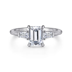 In this remarkable 0.35ct diamond engagement ring setting, a hidden halo encircles your 1.5ct emerald cut center stone. Matching baguette side stones create a classic 3 stone design. The 14K white gold band features a straight silhouette, high polish finish, and milgrain detailing along the inner shank.