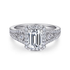 Intricate pave diamond and milgrain details elevate the tapered band of this white gold halo engagement ring which showcases an emerald cut diamond.